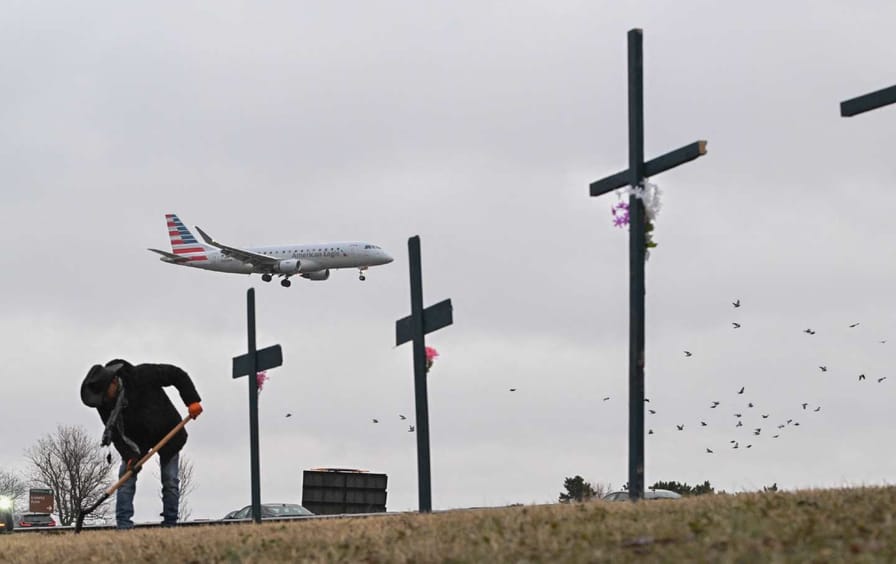 Roberto Marquez from Dallas, Texas, sets up a makeshift memorial for the victims of the crash of an American Airlines flight and a Blackhawk helicopter in Arlington, Virginia.