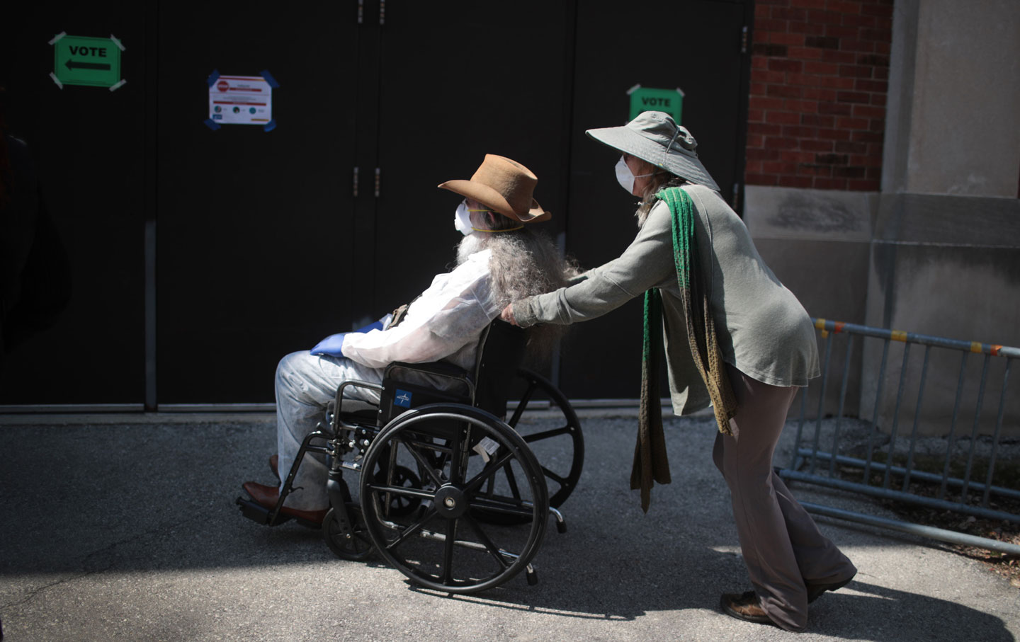 A person in wheelchair, being pushed by another person, waiting to cast their vote in the Wisconsin primary election