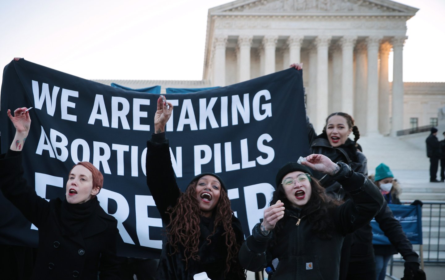 Protesters hold a huge banner reading "We Are Taking Abortion Pills Forever" in front of the Supreme Court Building.