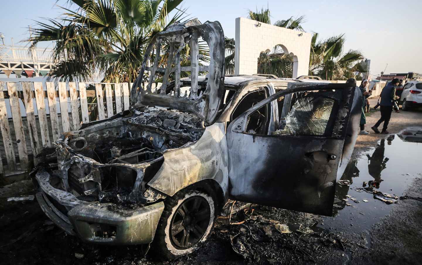 在加沙地带中部，巴勒斯坦人站在一辆车旁，世界中央厨房 (WCK) 的员工在以色列空袭中丧生。