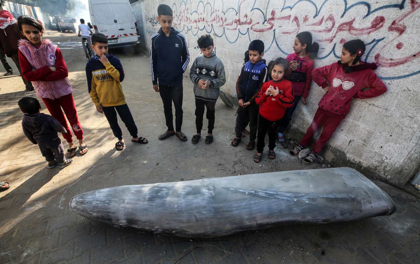 Palestinians stand next to an unexploded bomb dropped by an Israeli F-16 warplane in Deir al-Balah, central Gaza Strip, on January 1, 2024