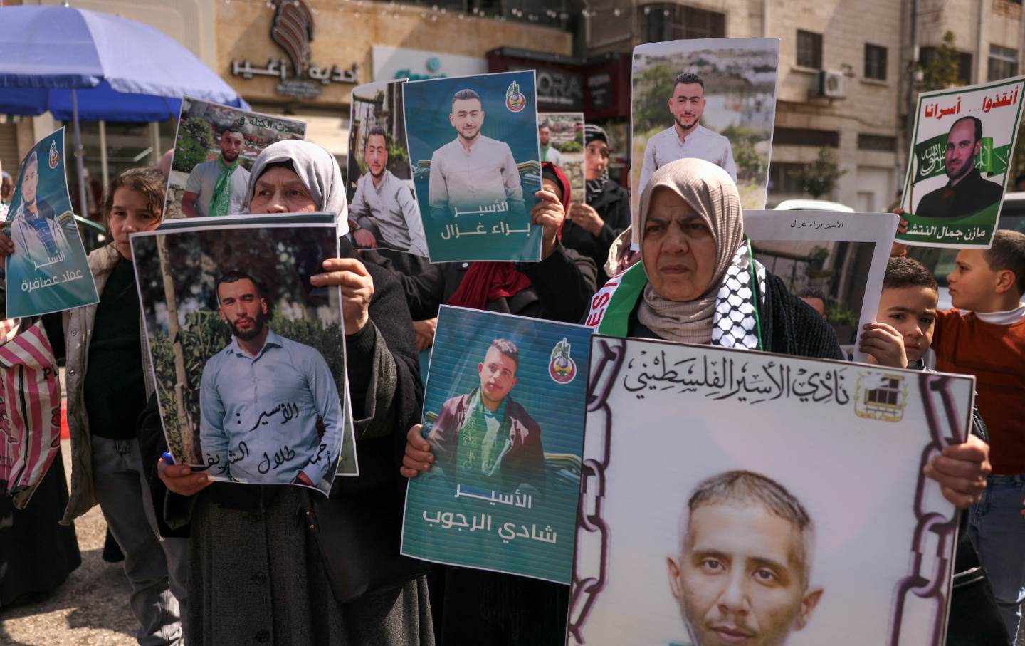 Relatives and friends of Palestinians imprisoned in Israel hold up signs at a rally calling for the release and return of the bodies of those killed in prison, in Hebron in the occupied West Bank on February 27, 2024.
