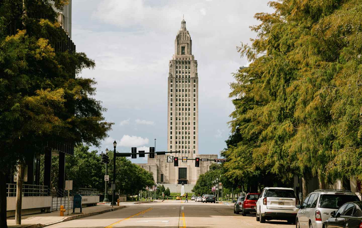 A view of the tower of the Louisiana State Capitol, framed by trees.