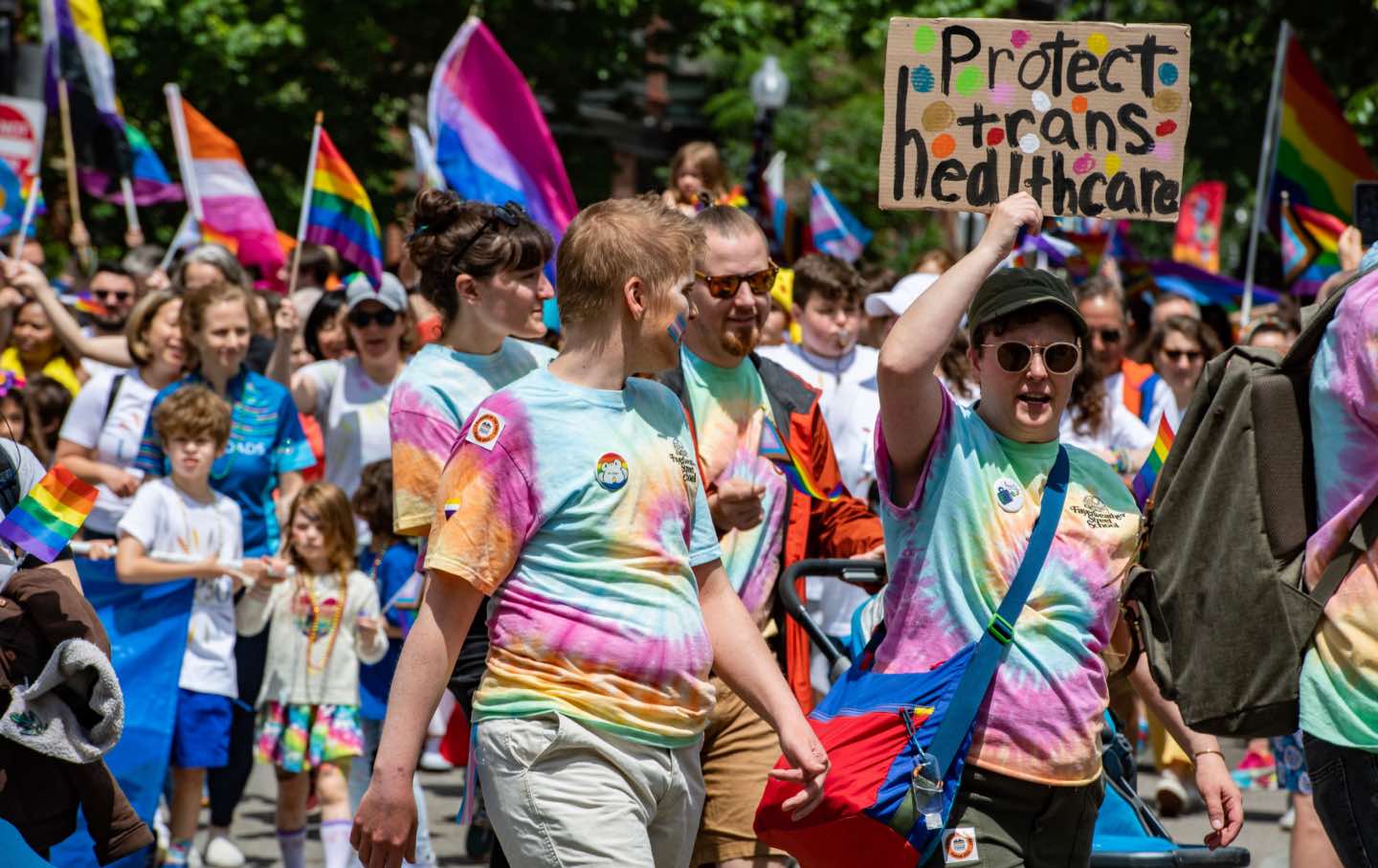 Marchers in tie-dyed t-shirts hold a sign reading 
