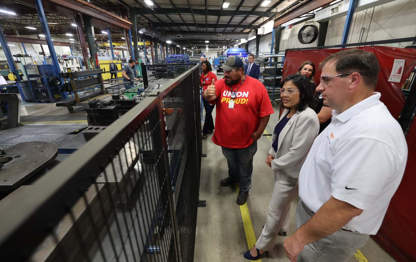 Workers stand alongside Acting Labor Secretary Julie Su looking at an assembly line.