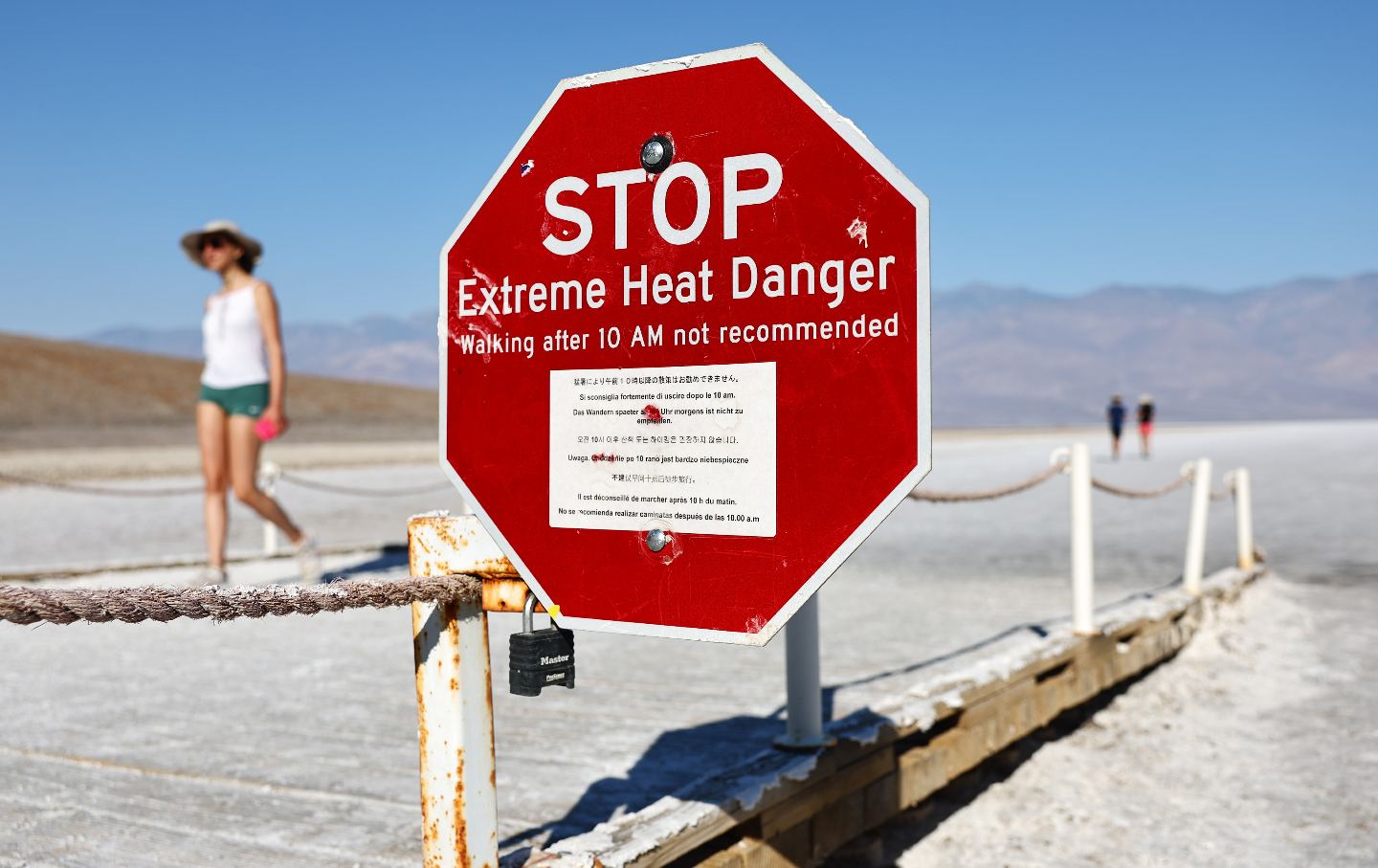 Visitors walk near a “Stop Extreme Heat Danger” sign in Badwater Basin salt flats.