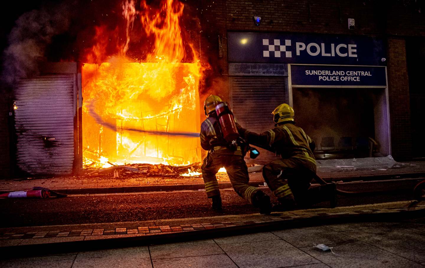 Firefighters spray water on a police station fire during a riot