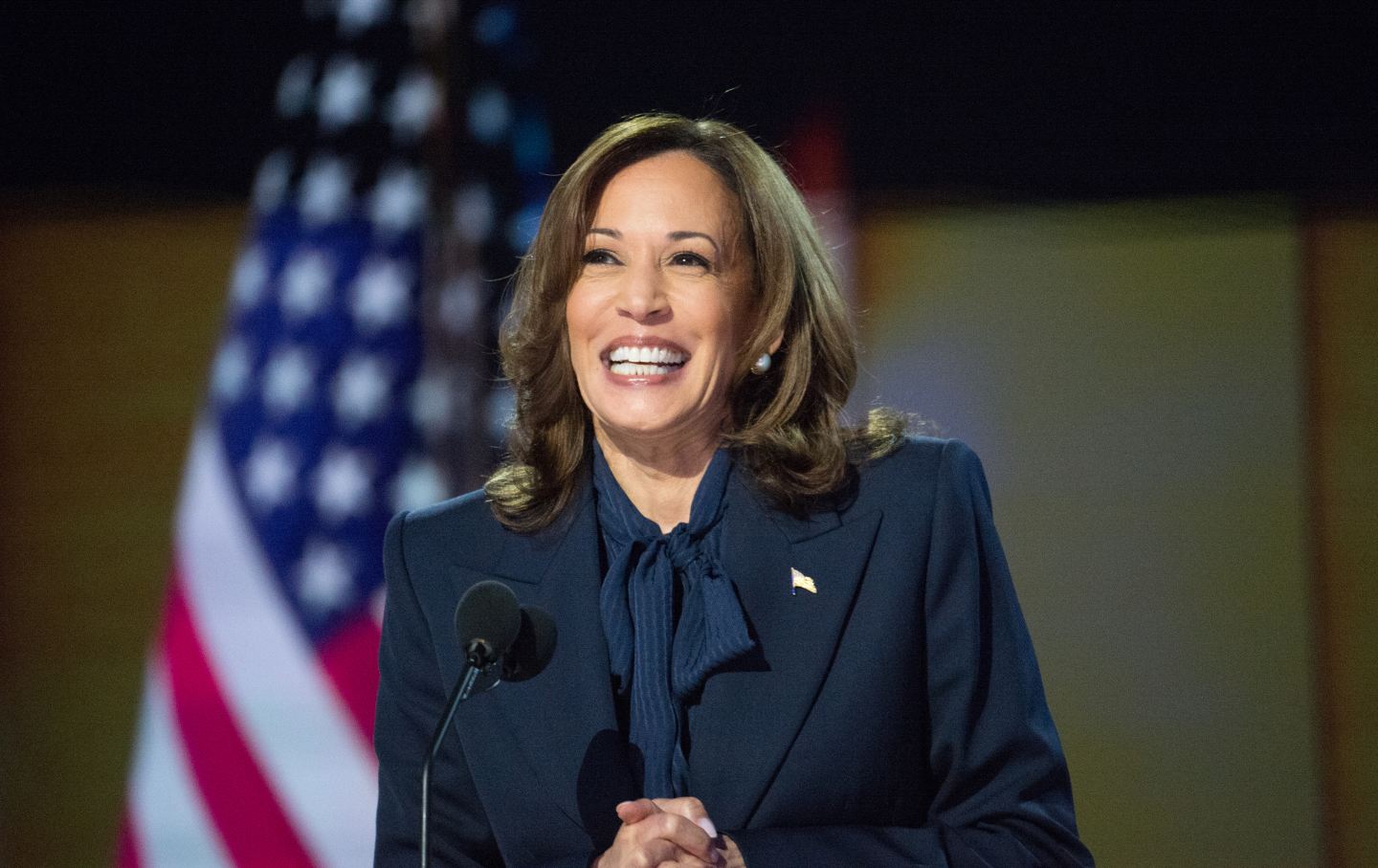 A close-angle shot of Vice President Kamala Harris smiling in front of an American flag onstage at the Democratic National Convention.