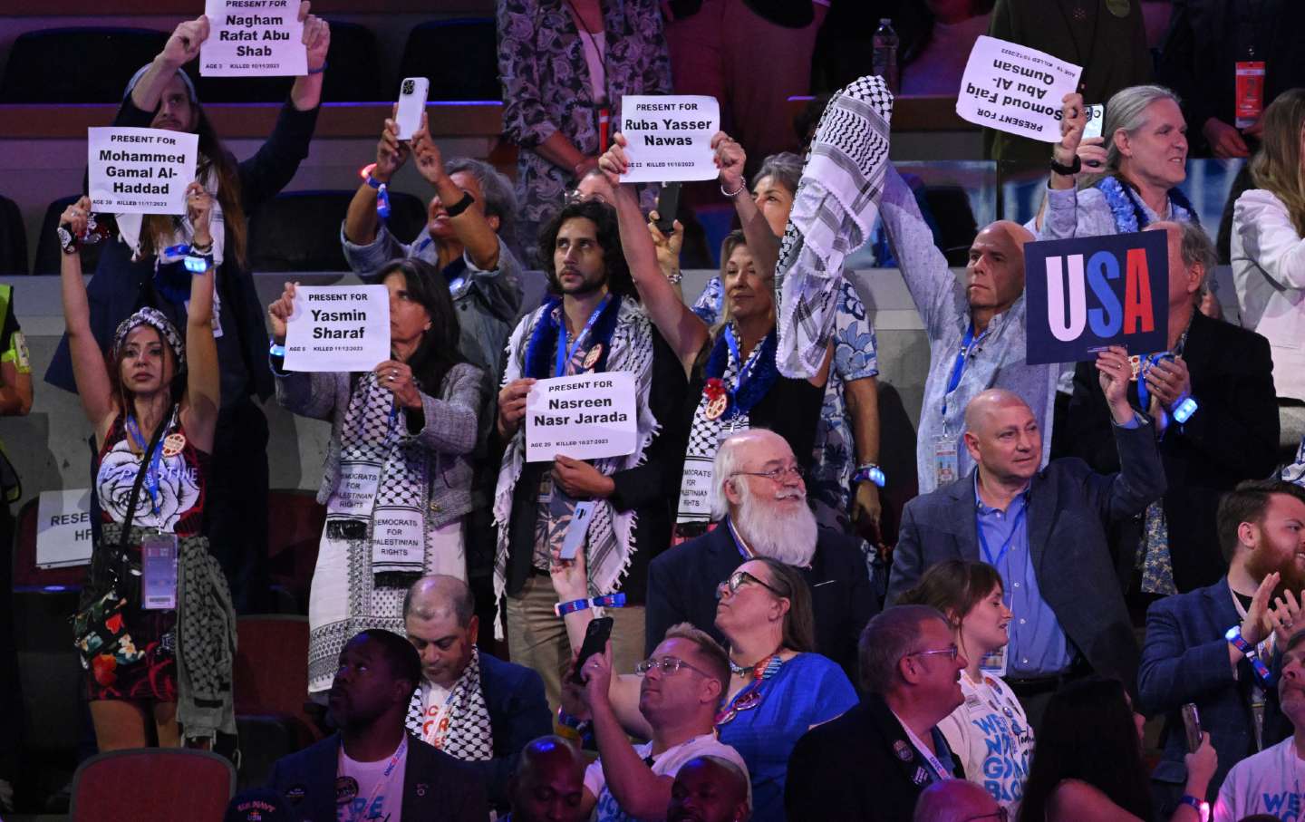 Delegates wearing keffiyehs hold up signs with the names of people who died in the Gaza war on the second day of the Democratic National Convention at the United Center in Chicago on August 20, 2024.