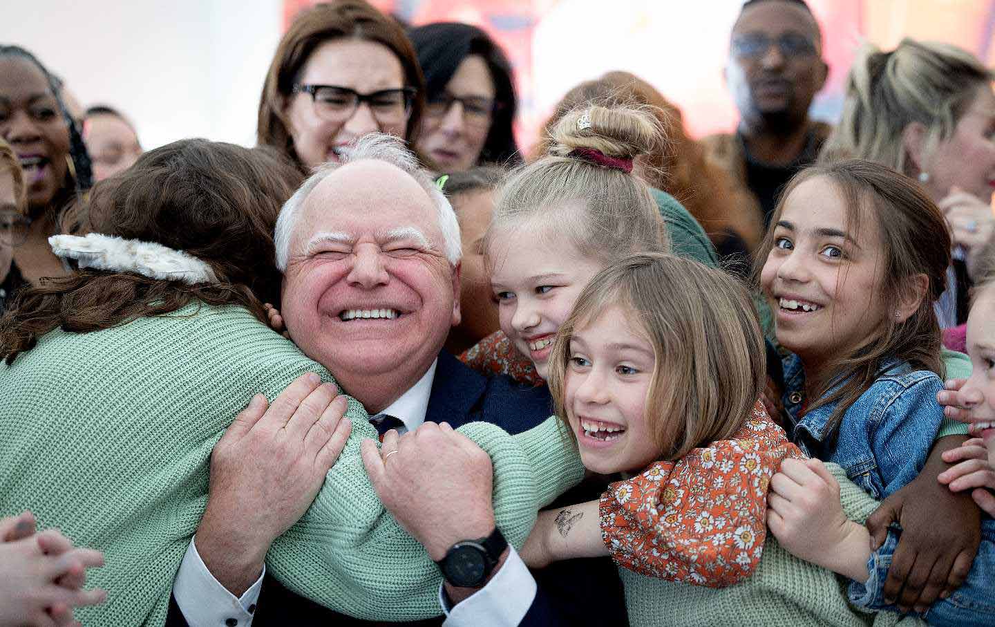 Governor Tim Walz gets a huge hug from students at Webster Elementary in Minneapolis, after he signed into law a bill that guarantees free school meals for every student in Minnesota's public schools.