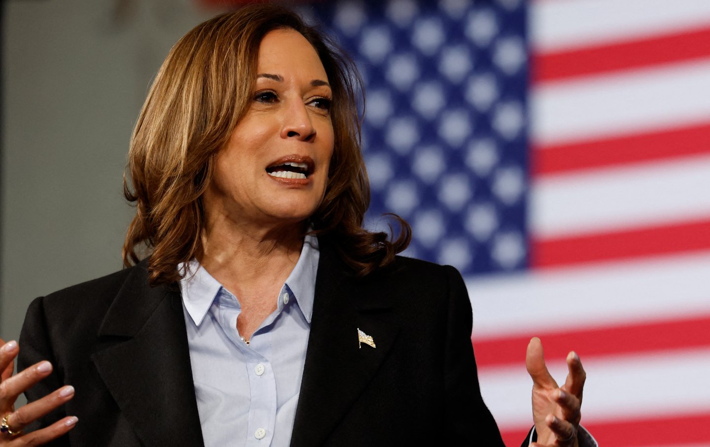 VP candidate Kamala Harris in mid speech, standing in front of an American flag.