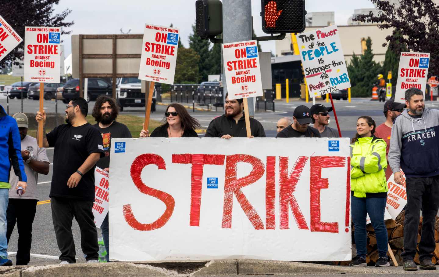 Workers holding picket signs stand in the street, with a banner reading STRIKE in red.