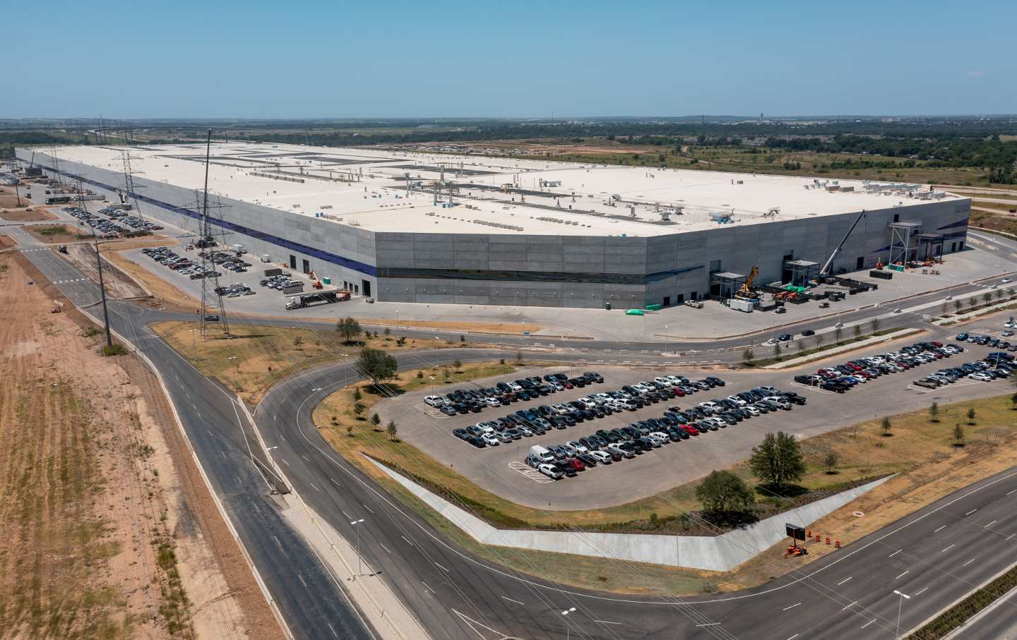 An aerial view of Tesla’s factor in Austin, Texas, ringed by parking lots with cars parked inside.