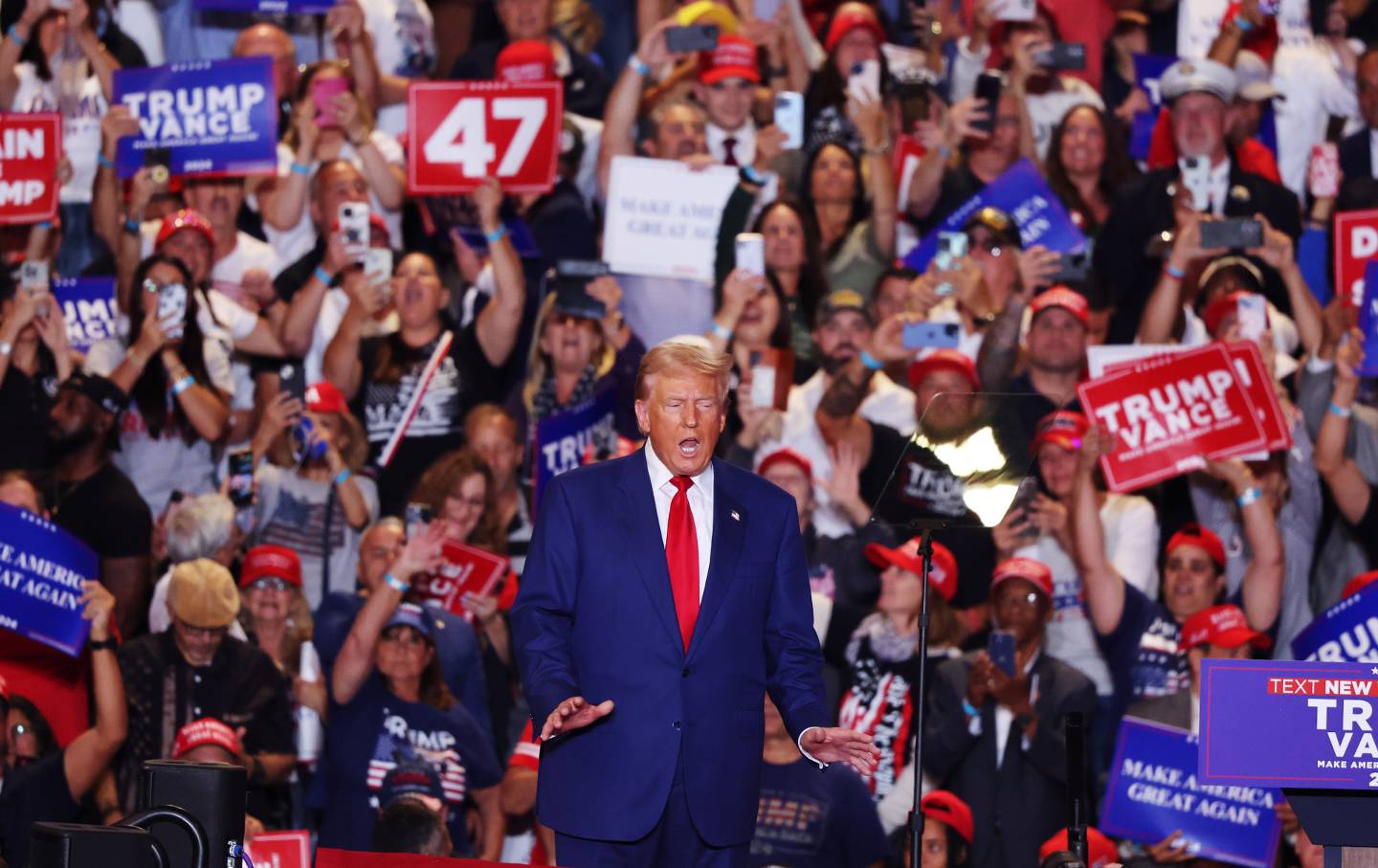 Former president Donald Trump in front of a large crowd at a rally.