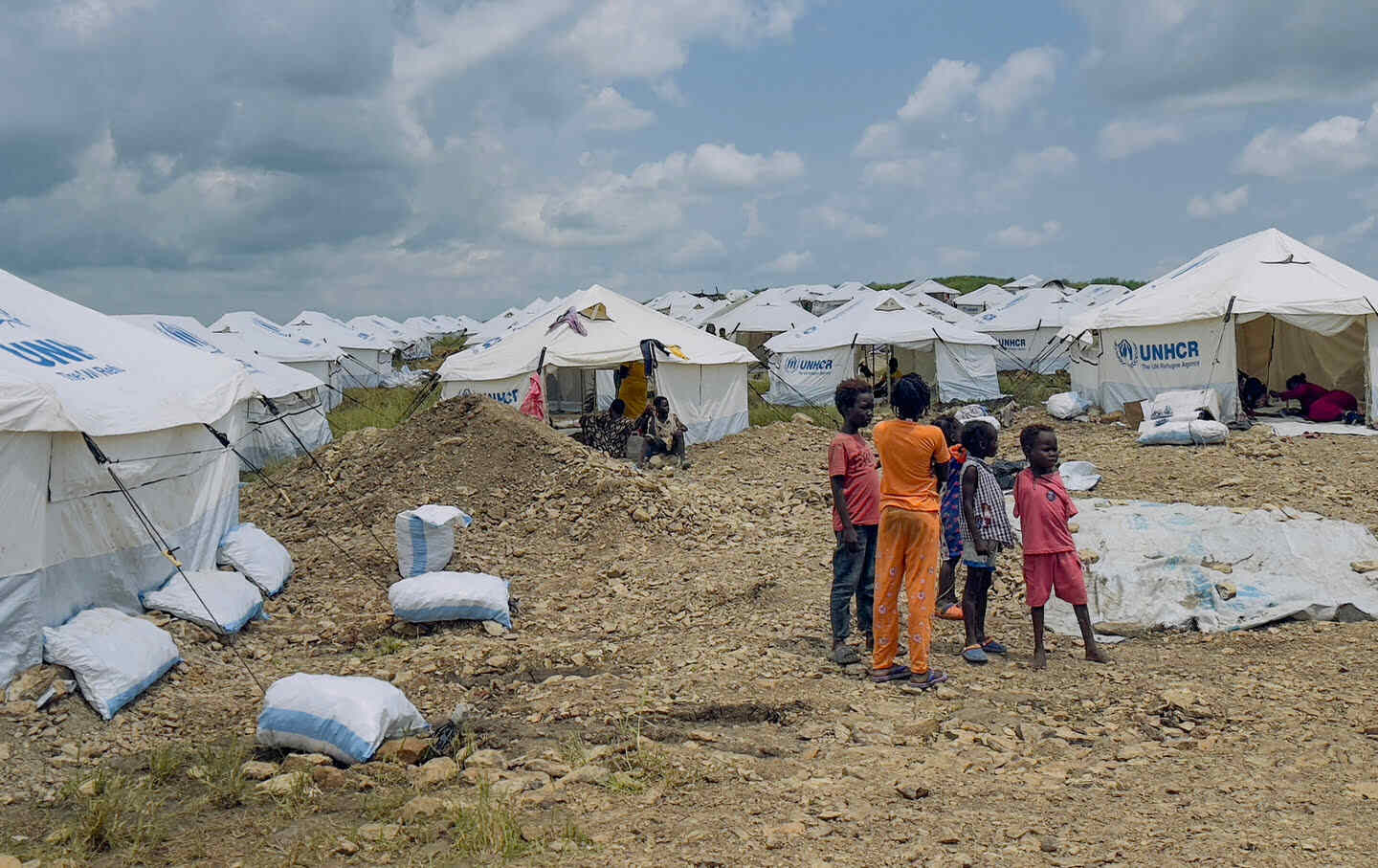 Displaced Sudanese children who have returned from Ethiopia gather amid tents fortified against heavy rain by sandbags, in a camp run by the United Nations Refugee Agency in Sudan's border town of Gallabat, on September 4, 2024.