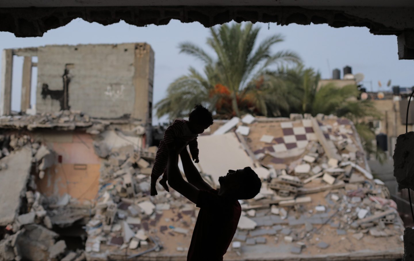 A man plays with a baby as Palestinians struggle with power outages due to Israeli attacks that destroyed the infrastructure in Gaza City, Gaza on October 13, 2024.