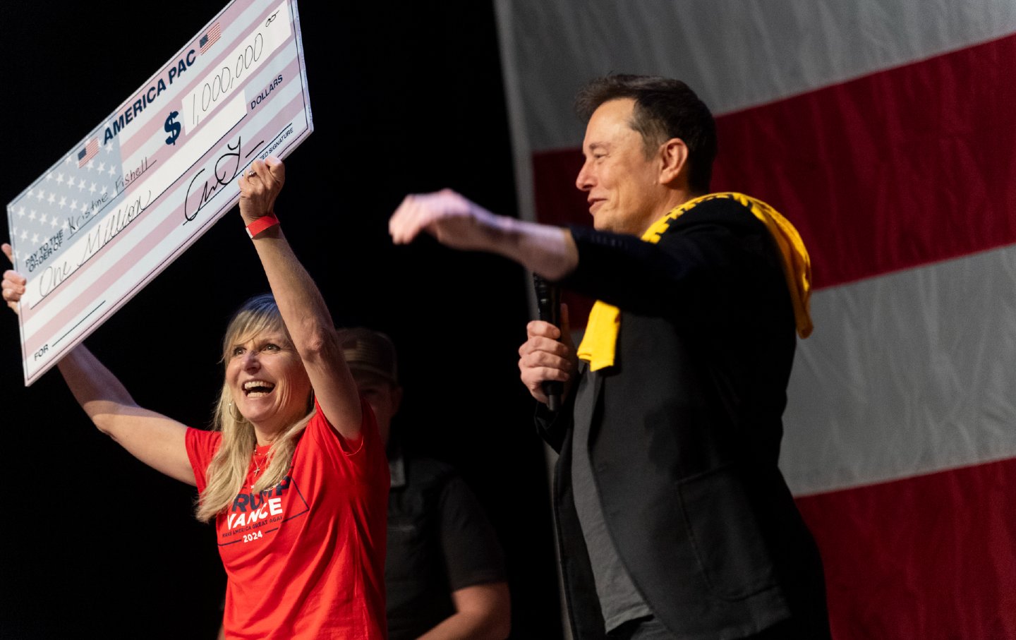 Elon Musk presents Kristine Fishell with a check for $1 million during a town hall at the Roxain Theater on October 20, 2024 in Pittsburgh, Pennsylvania.