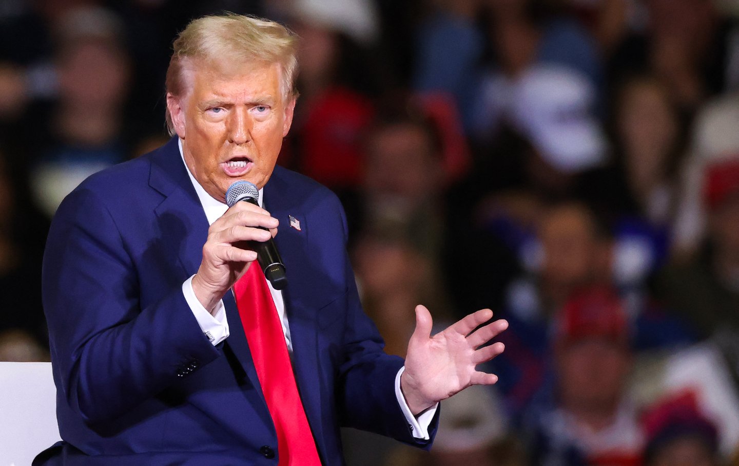 Former President Donald Trump holding a microphone in front of a crowd.