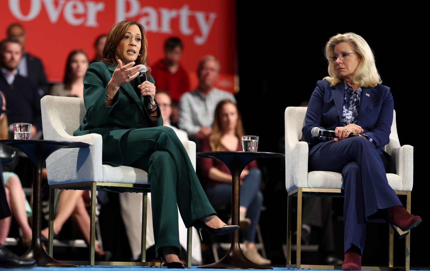 Vice President Kamala Harris and former Rep. Liz Cheney in arm chairs on a stage holding microphones.