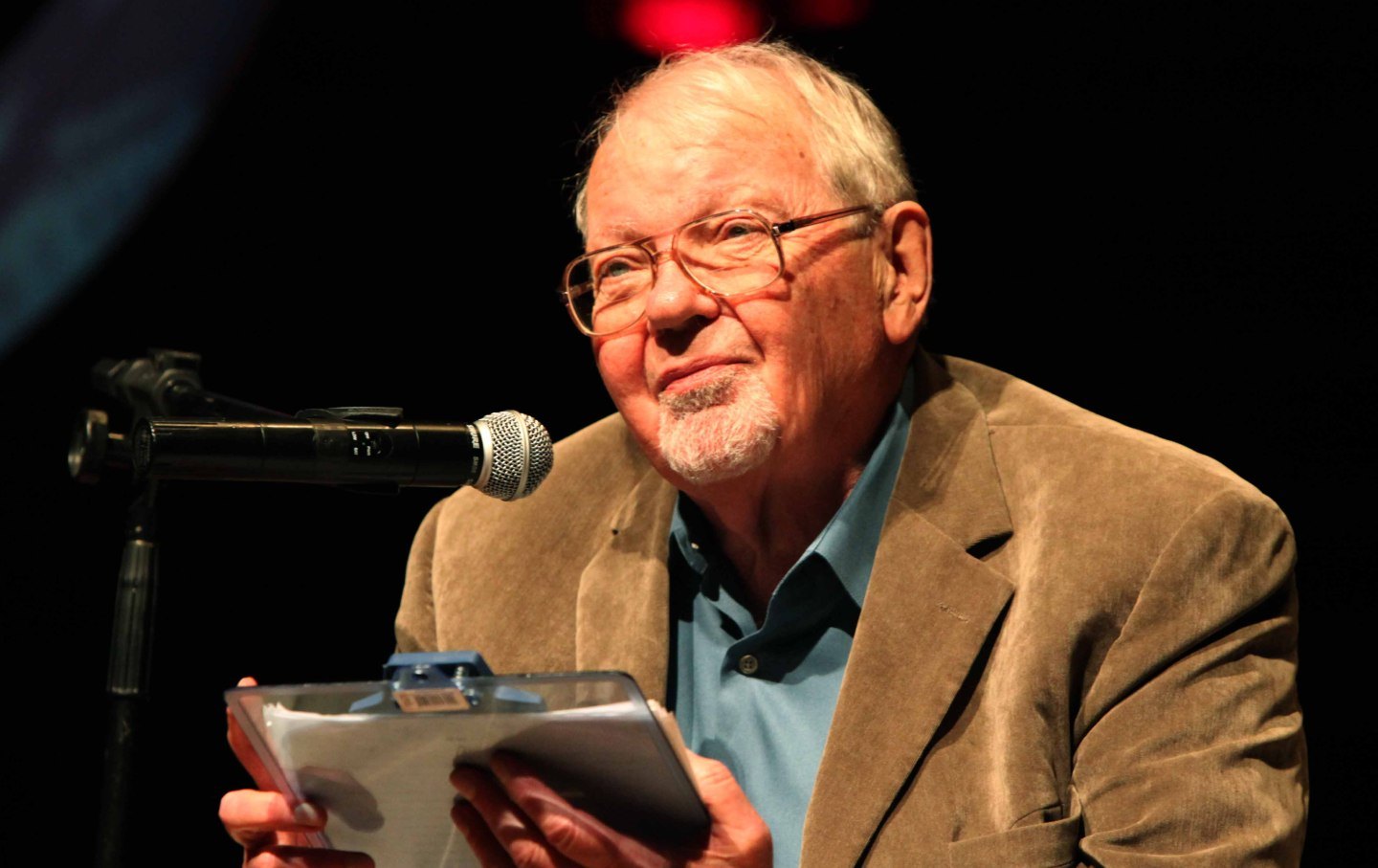 A close-up photo of Fredric Jameson smiling in front of a microphone.