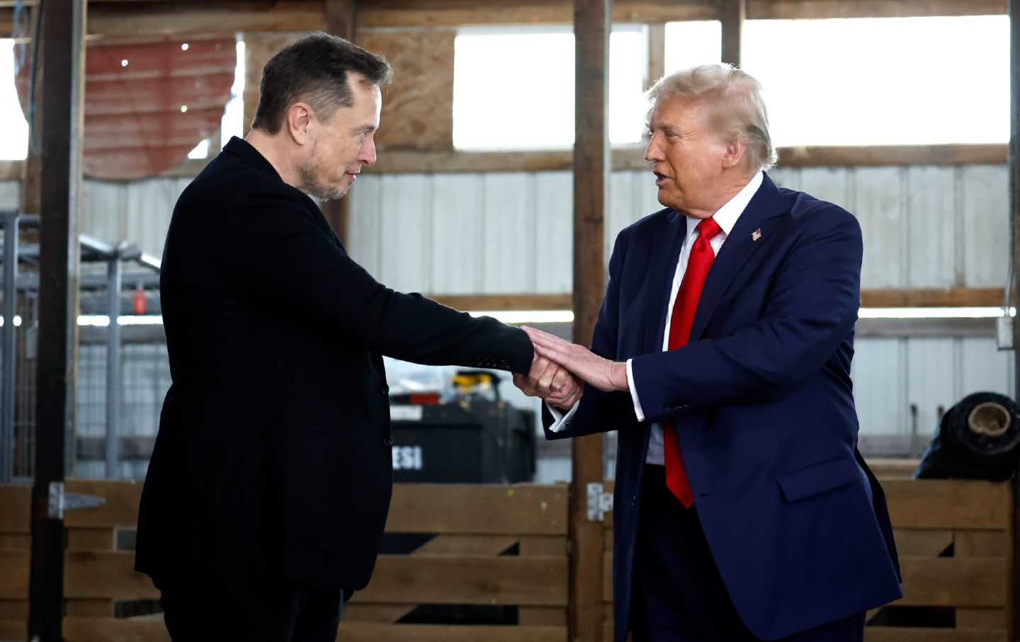 Elon Musk (Kiri) berjabat tangan dengan calon presiden dari Partai Republik, mantan presiden Donald Trump, di belakang panggung selama rapat umum kampanye di lapangan Butler Farm Show pada 5 Oktober 2024, di Butler, Pennsylvania.