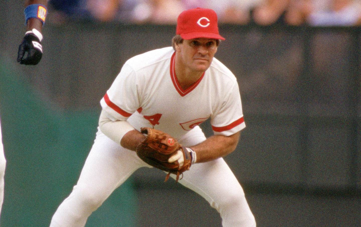 Pete Rose holding a baseball mitt in position during a Cincinnati Reds game.