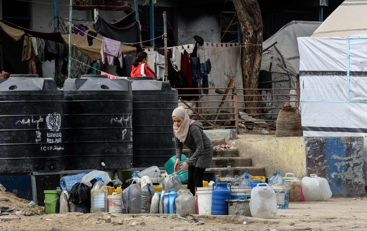 A woman arranges empty bottles as displaced Palestinians struggle to survive while Israeli attacks continue in Khan Yunis, Gaza on November 18, 2024.