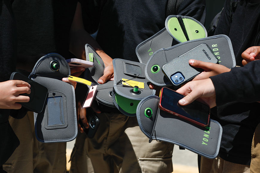 Students unlock the pouch that secures their cell phones during the school day.