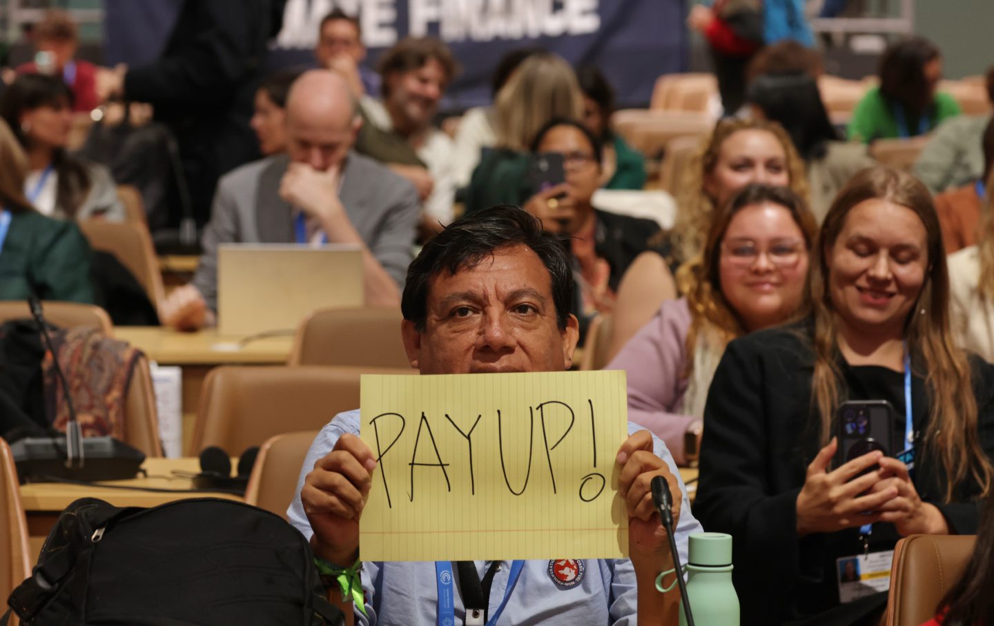 Activists, including one holding a piece of paper with “Pay Up!” written on it, in reference to demands for climate finance for developing countries, arrive to attend the “People’s Plenary on day 10 at the UNFCCC COP29 Climate Conference on November 21, 2024, in Baku, Azerbaijan.