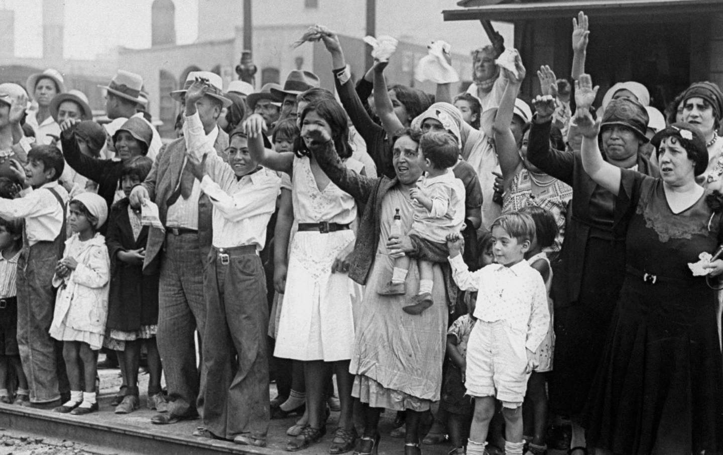 Black and white photo of people waving to a train.