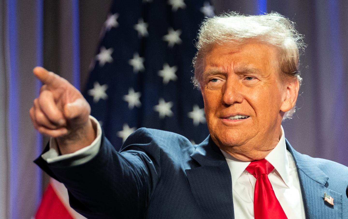 President Donald Trump pointing in front of an American flag.