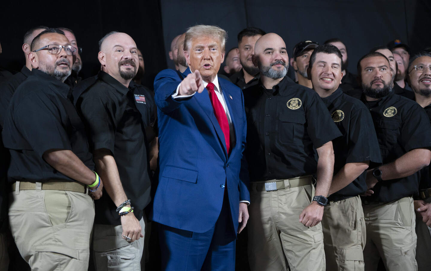 Donald Trump points at a group of photographers and says, “Fake news” while posing with the National Border Patrol Council during a campaign rally on October 13, 2024, in Prescott Valley, Arizona.