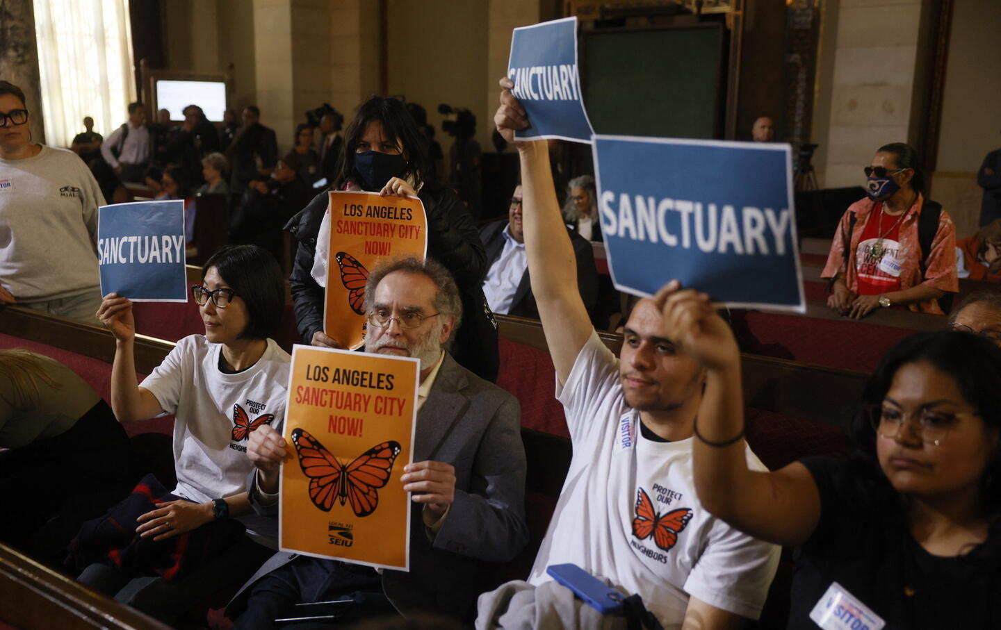 People in the audience hold up signs in support of immigrants as the Los Angeles City Council considers a "sanctuary city" ordinance during a meeting at City Hall in Los Angeles, California, on November 19, 2024.