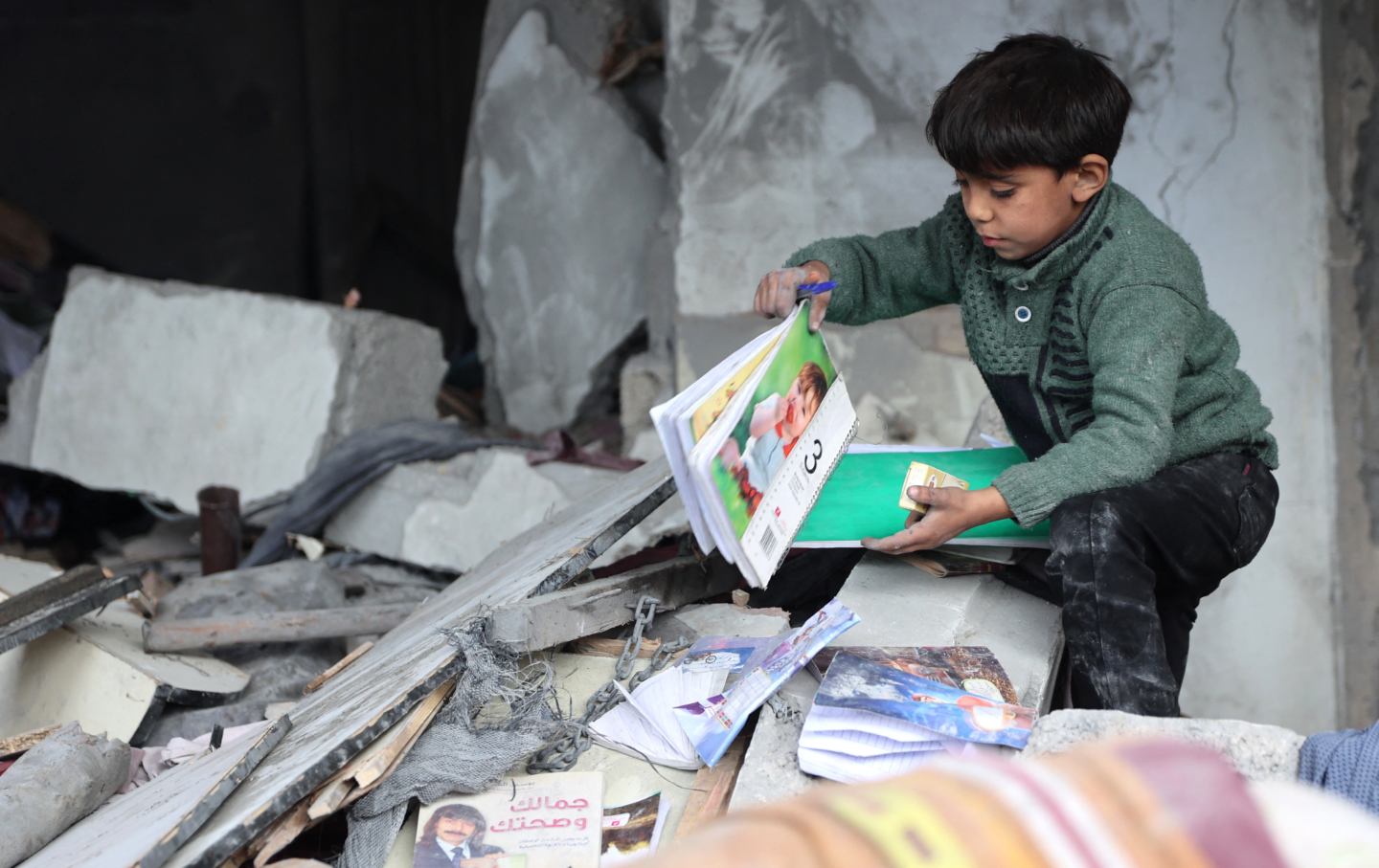 A child recovers books from the rubble of a building hit in Israeli strikes the previous night in Jabalia in the northern Gaza Strip, on January 16, 2025.