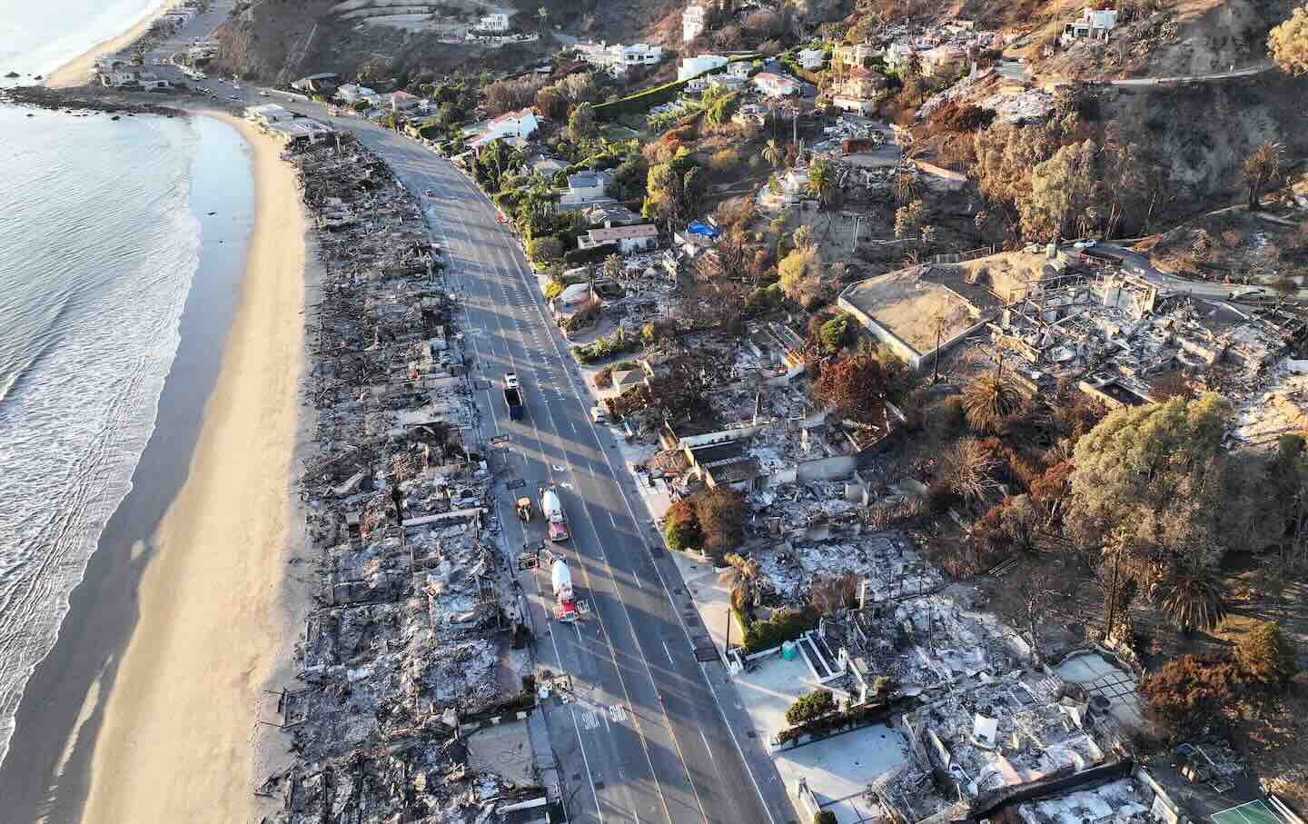 An aerial view of utility trucks near beachfront homes that burned in the Palisades Fire as wildfires cause damage and loss through the LA region on January 15, 2025. (Photo by Mario Tama / Getty Images)