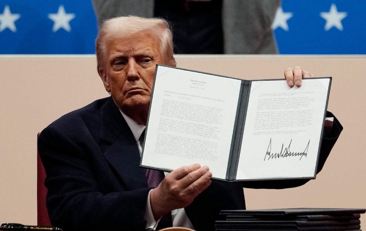 Donald Trump memegang perintah eksekutif yang ditandatangani pada parade pelantikan presiden ke-60 di Capital One Arena di Washington, DC.