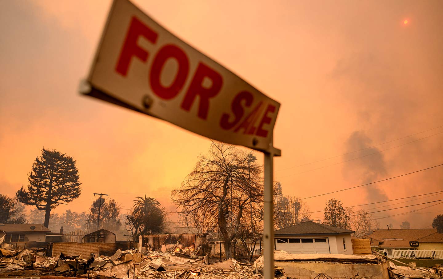 A “For Sale” sign remains as homes smolder during the Eaton fire in the Altadena area of Los Angeles County, California, on January 8, 2025.