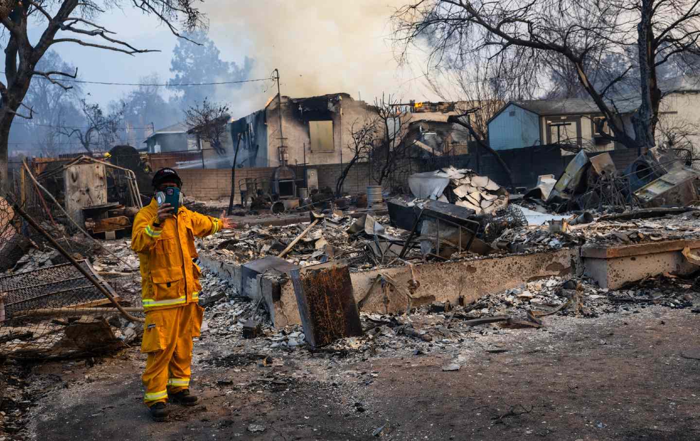 A reporter works in front of a home burned by the Eaton Fire in Altadena, California, on January 9, 2025.