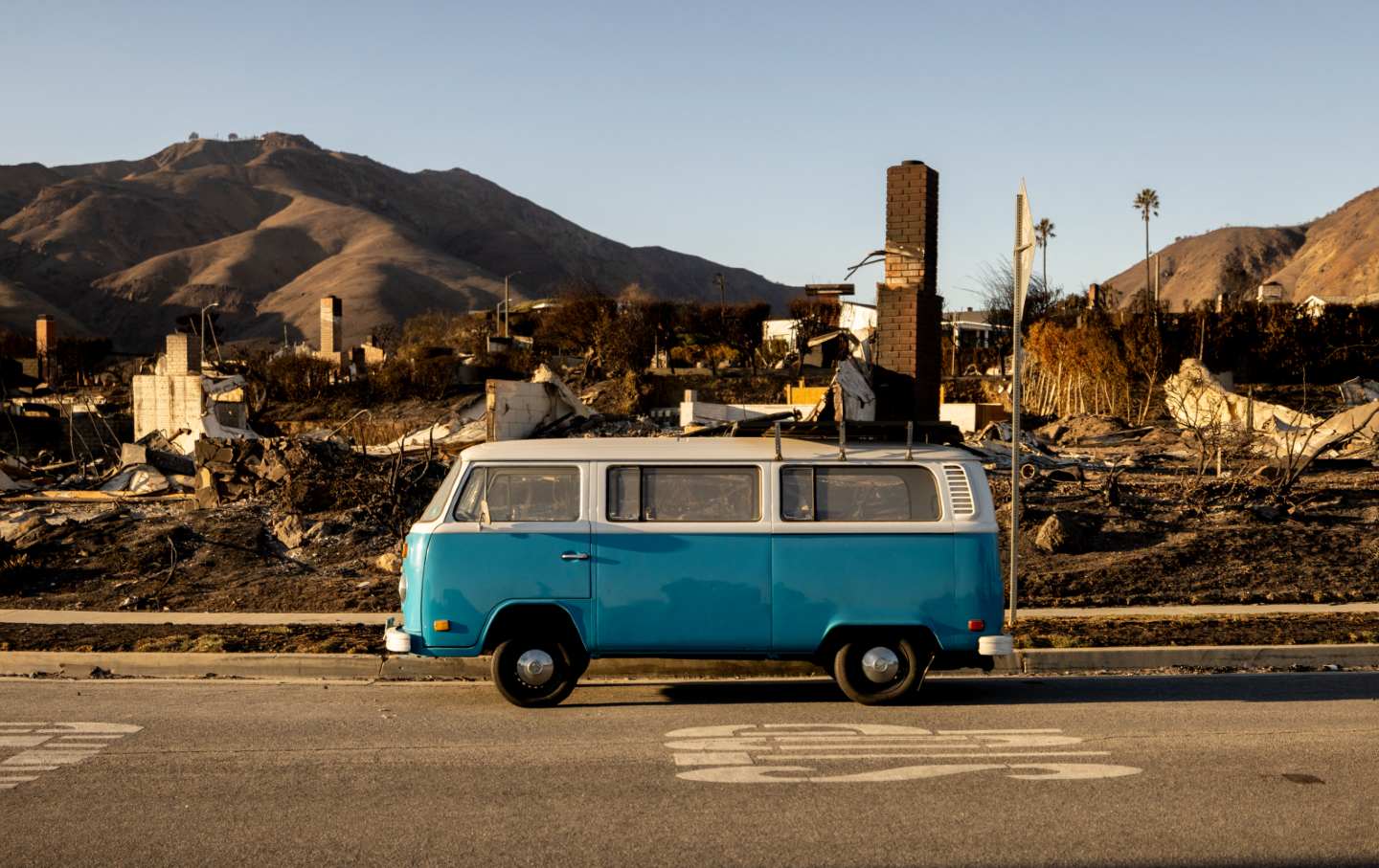 A blue Volkswagen van sits intact on a street amid homes destroyed by the Palisades Fire in Malibu, California, on January 15, 2025.