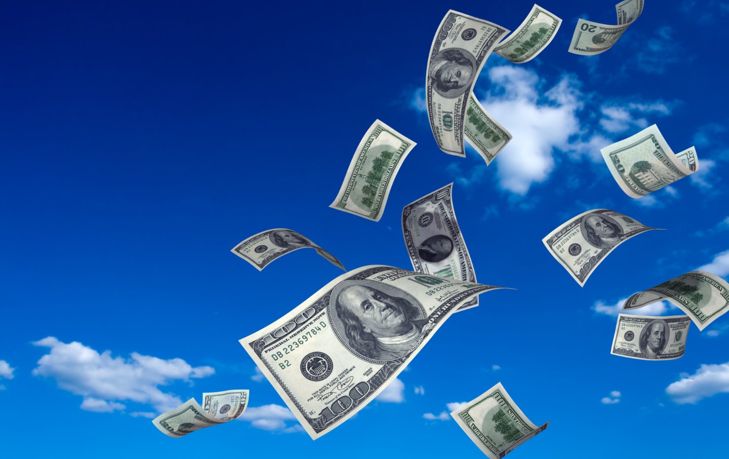 Hundred-dollar bills fly off into a sunny blue sky.