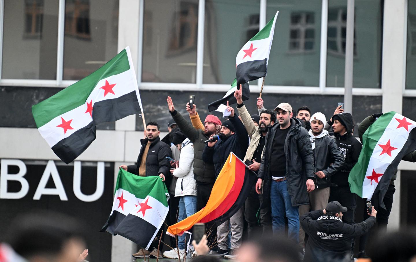 Members of the Syrian community hold flags of Syria and Germany as they rally on December 8, 2024, in Berlin.