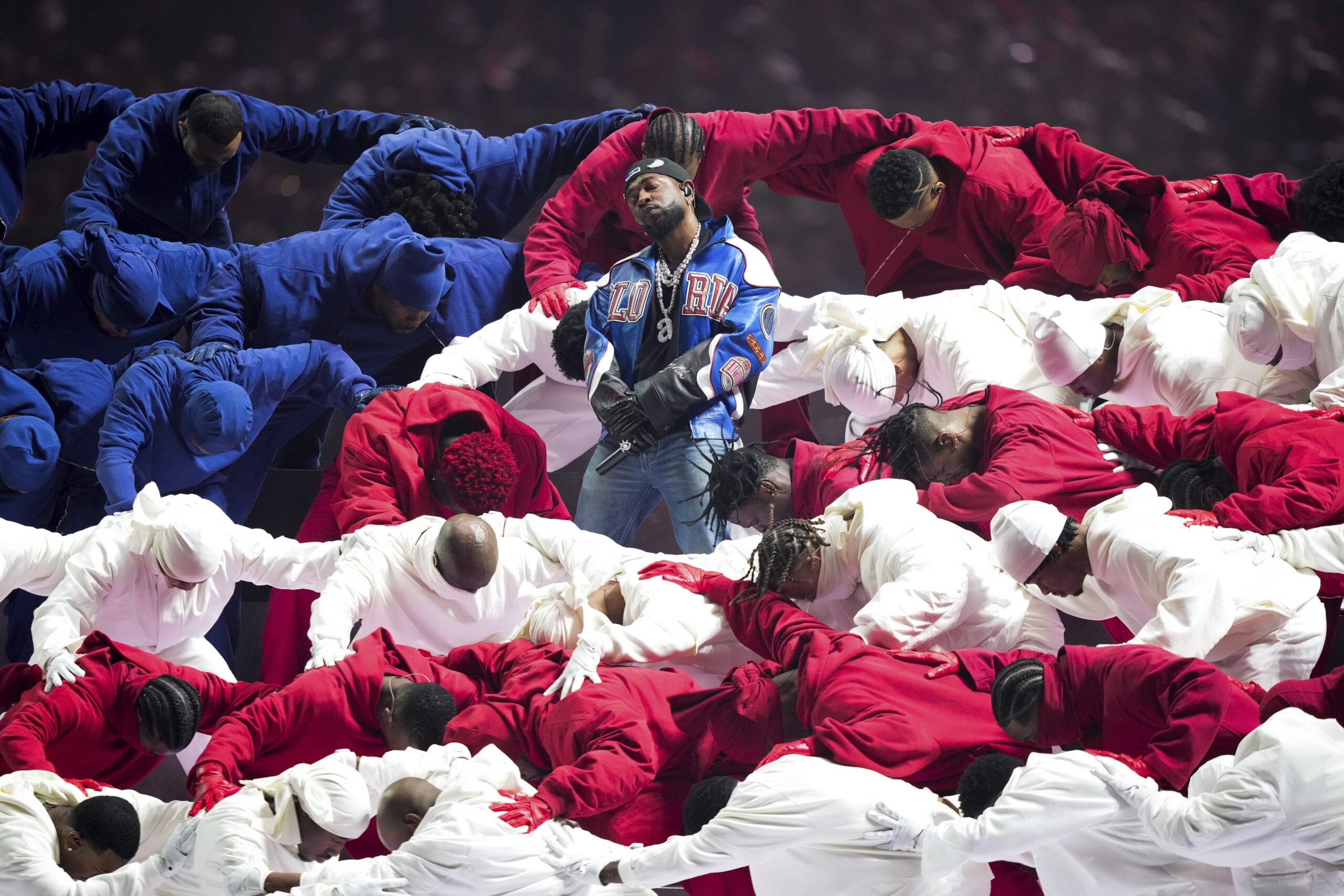 Kendrick Lamar stands center amid Black dancers in red, white and blue tracksuits forming an American flag during his halftime performance at the NFL Super Bowl 59 football game.