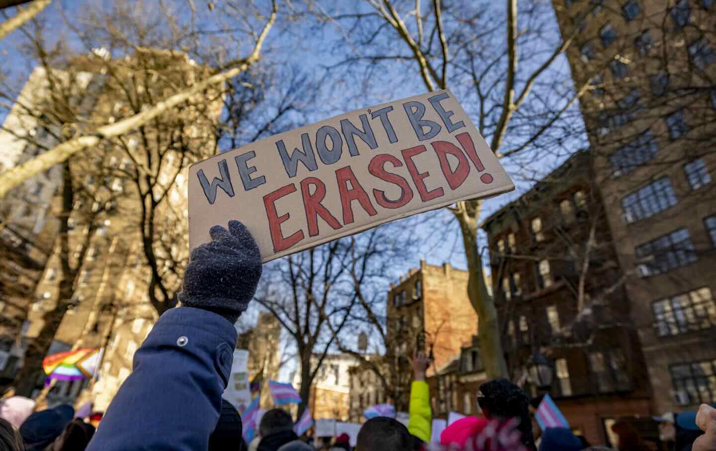 A protester holds up a sign with the words “We won't be erased” as activists, politicians, and others gather for a rally outside of the Stonewall Inn after the National Park Service eliminated references to transgender people from its Stonewall National Monument website on February 14, 2025, in New York City.