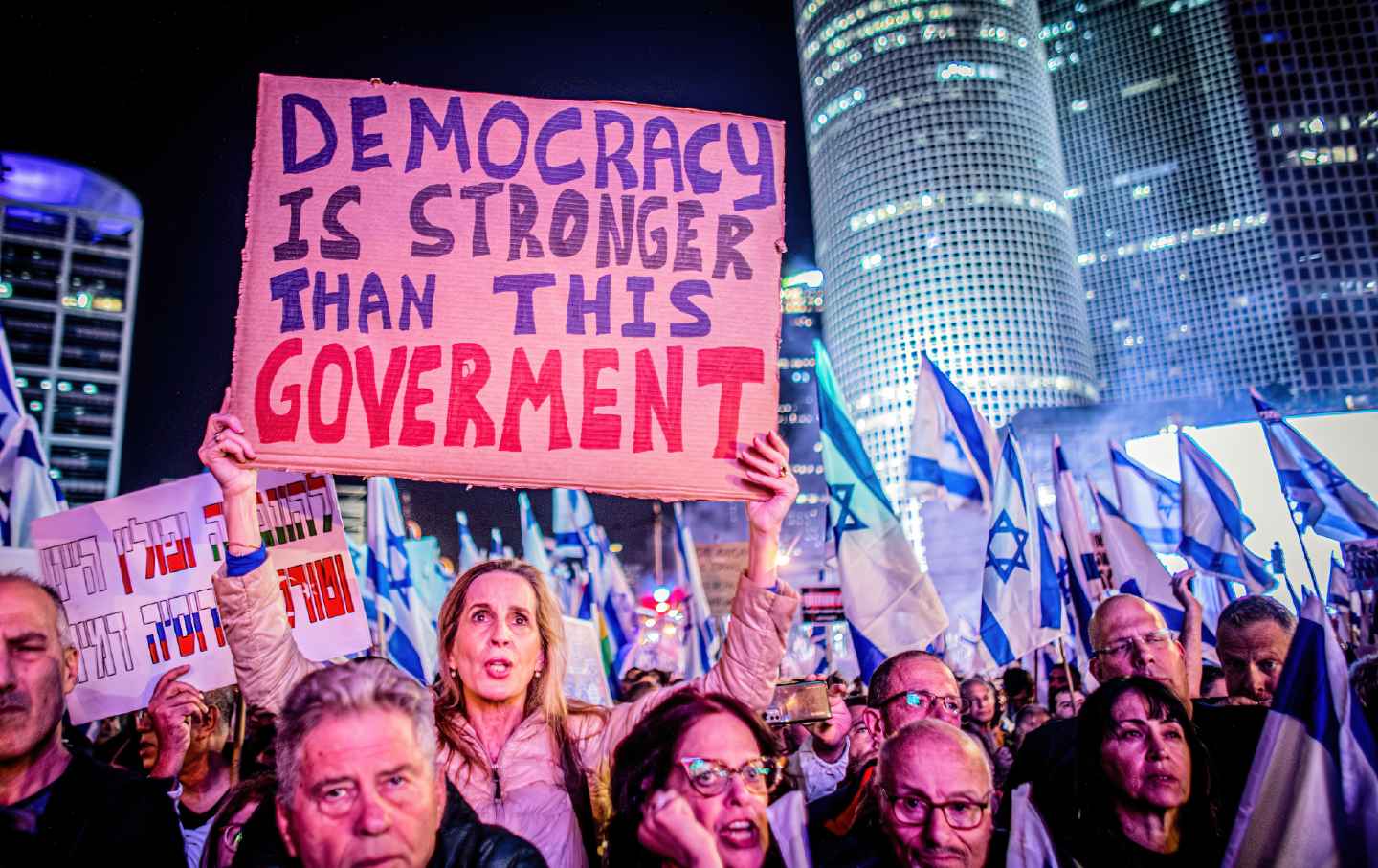 Israeli pro-democracy protester chants slogans while holding a placard during the demonstration.