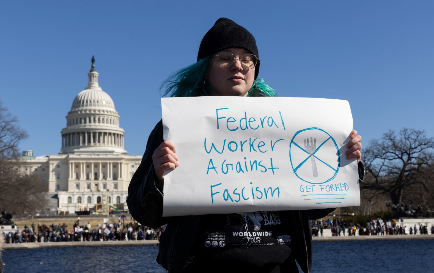 A protester holds a sign during the rally against the Donald Trump administration during “Not My President’s Day” protests at the Capitol Reflecting Pool in Washington, DC, on February 17, 2025.