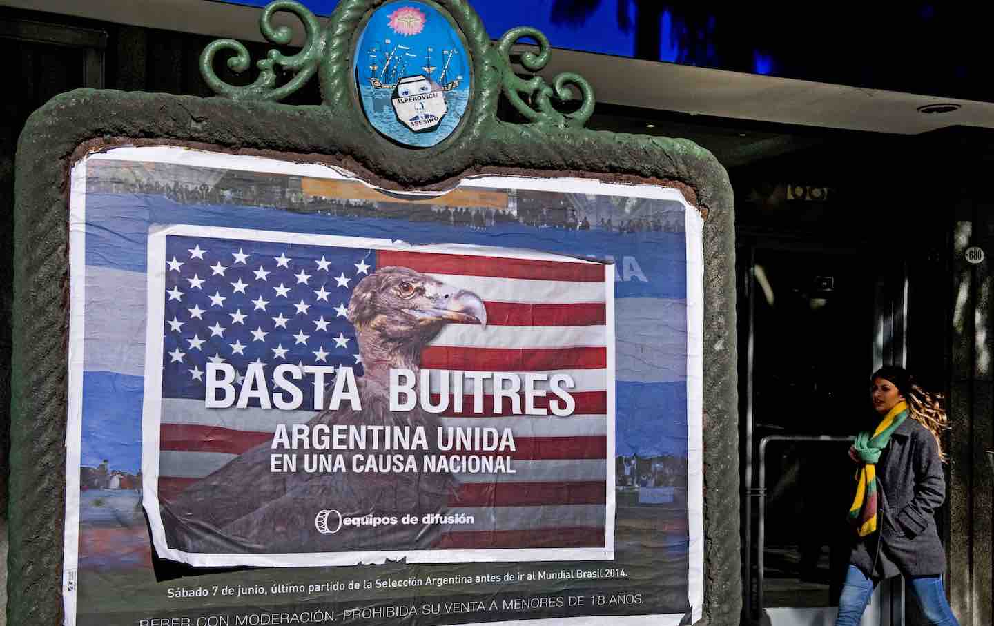 A woman passes by posters that read “Enough Vultures—Argentine united in a national cause” in Buenos Aires, 2014.