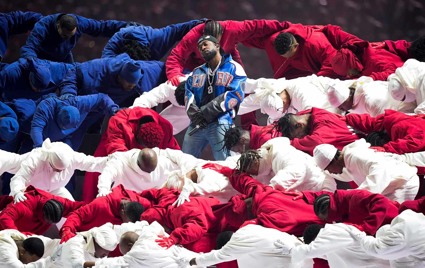 Kendrick Lamar stands amid Black dancers in red, white and blue tracksuits forming an American flag during his halftime performance at Super Bowl LIX.