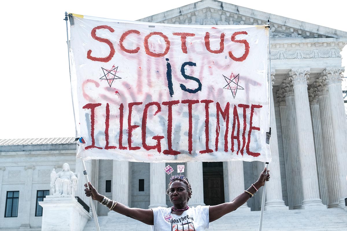 A woman demonstrates outside the Supreme Court on the day it ruled in favor of a former police officer who participated in the January 6 coup attempt.