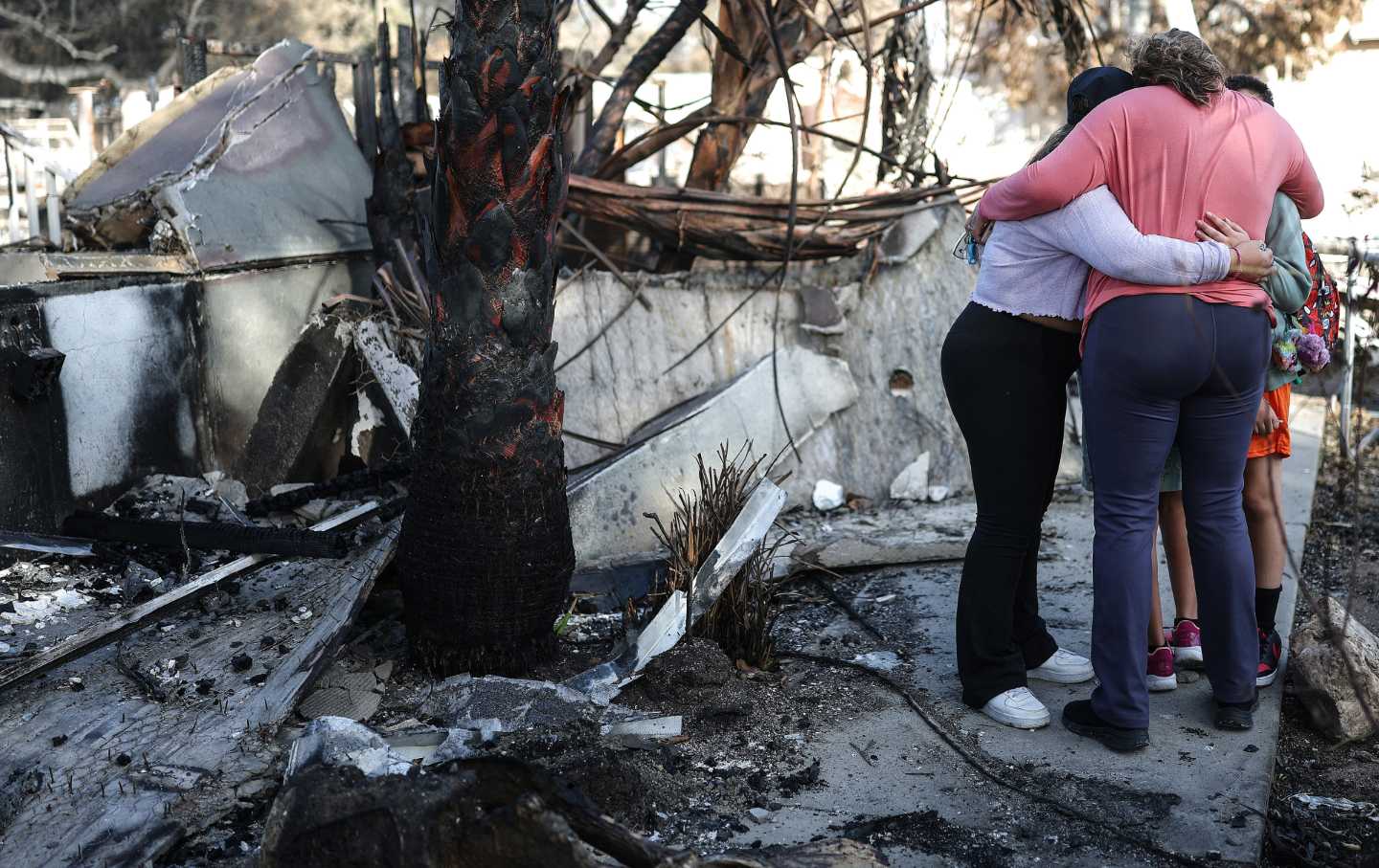 A family embraces in the aftermath of the Eaton Fire that claimed their home in Altadena, California.