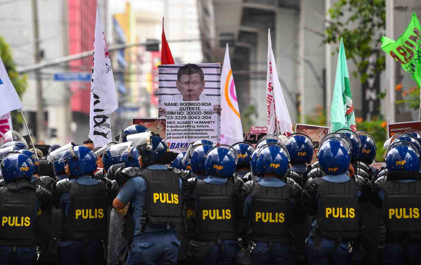 Protesters carrying a placard showing former president Rodrigo Duterte are blocked by anti-riot policemen near Malacanang palace in Manila, 2025.